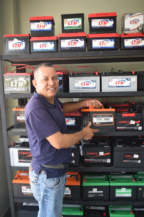 Asesor de Repuestos Carmelo revisando el inventario de baterías en el local